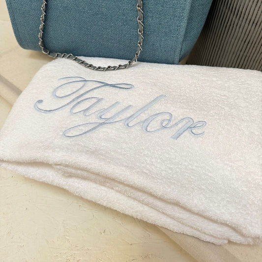  white towel with 'Taylor' monogram on a wooden surface.
