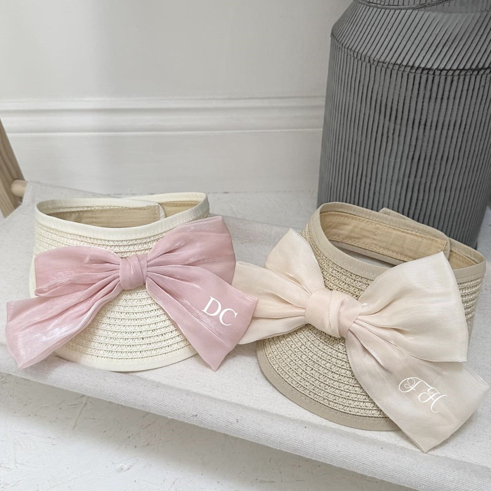 Two straw visors with large bows on a white surface