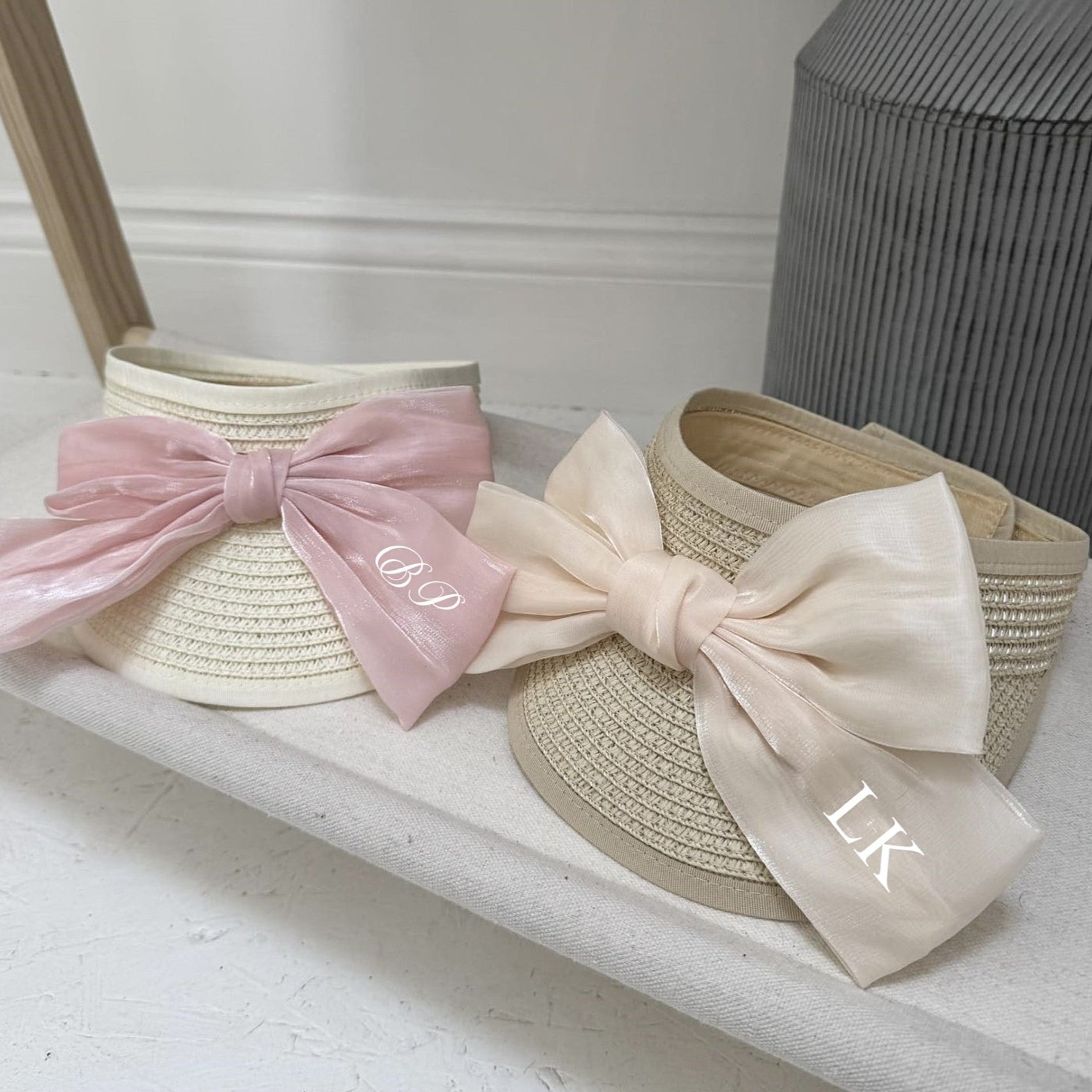 Two straw visors with large bows on a white surface personalised