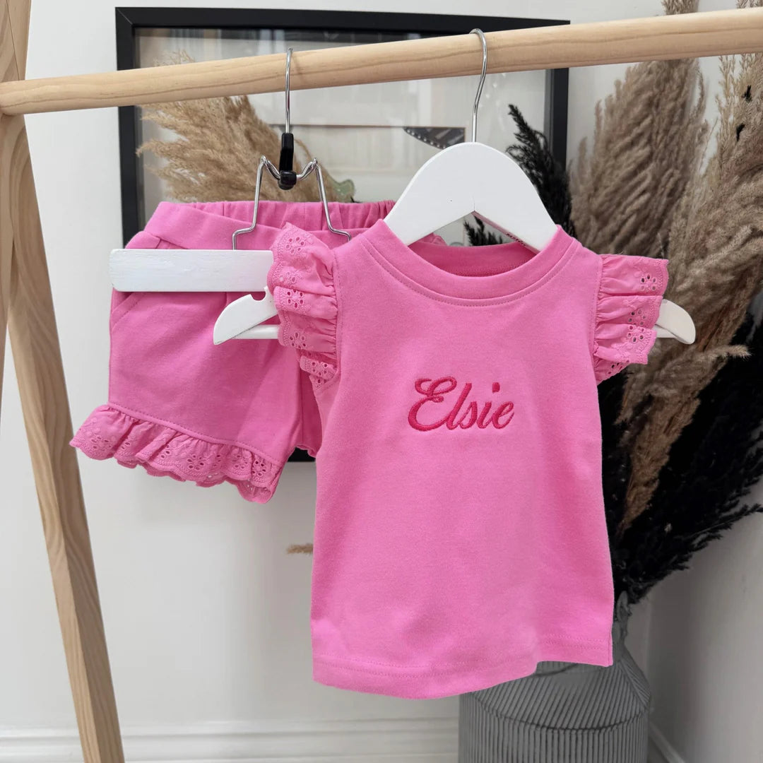 Pink children's outfit with 'Elsie' on a hanger against a neutral background
