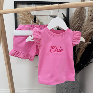 Pink children's outfit with 'Elsie' on a hanger against a neutral background