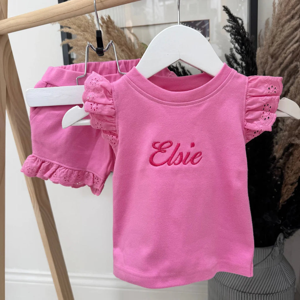 Pink children's outfit with 'Elsie' on a hanger against a neutral background