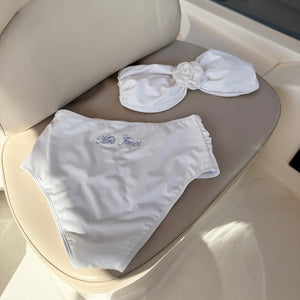 White bikini set with floral details on a boat seat