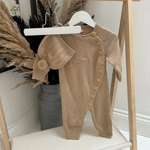 Brown baby romper with buttons on a white hanger against a neutral background