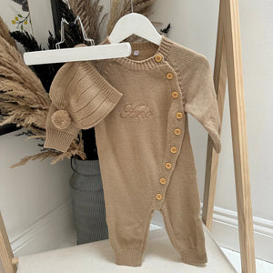Brown baby romper with buttons on a white surface