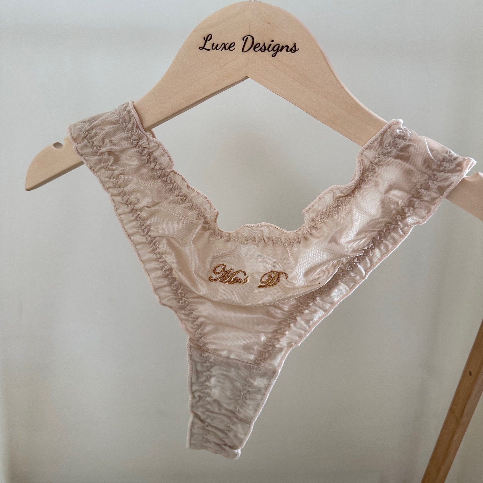Lace lingerie set on a hanger with 'Luxe Designs' branding against a light background