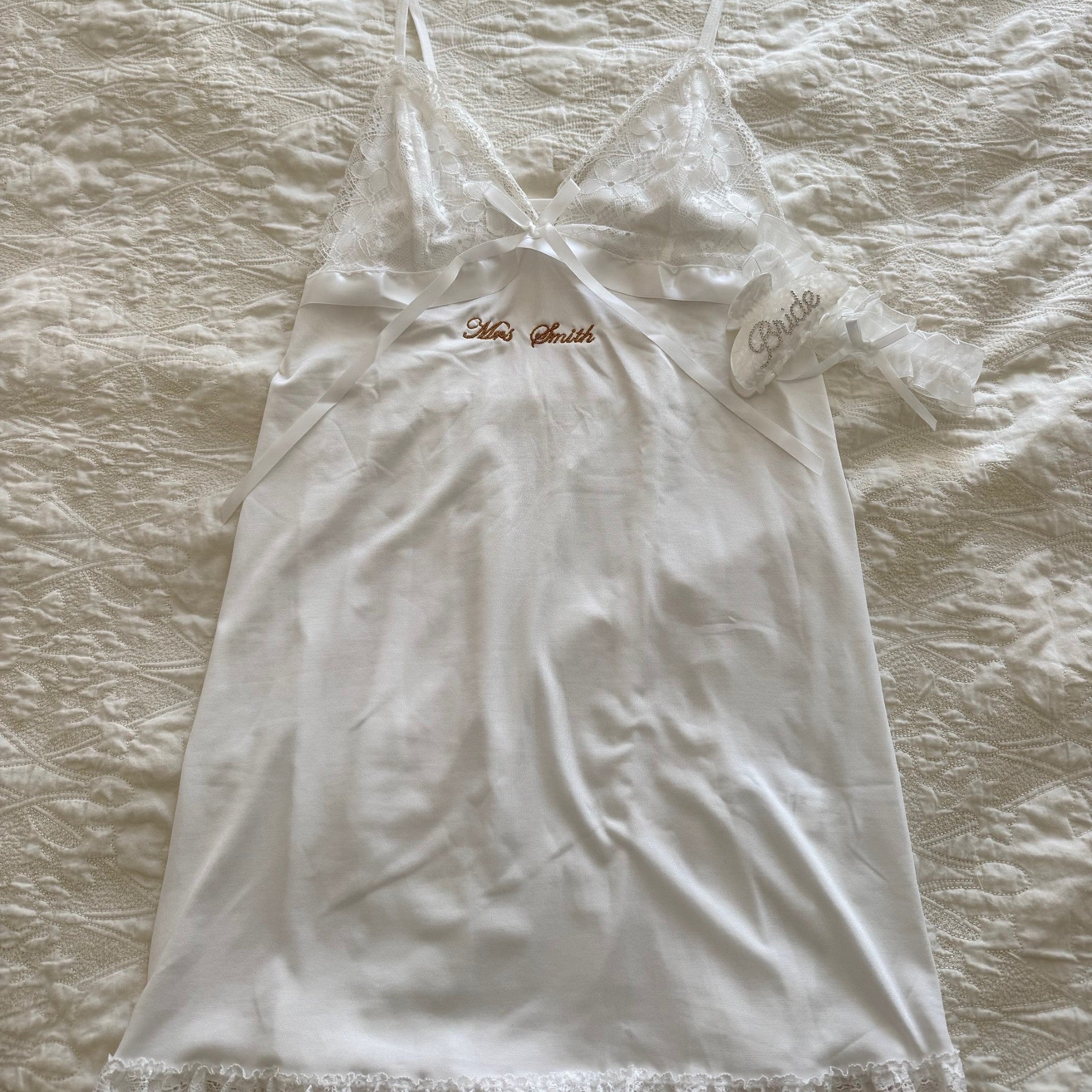 White lace nightgown on a wooden hanger against a textured beige background