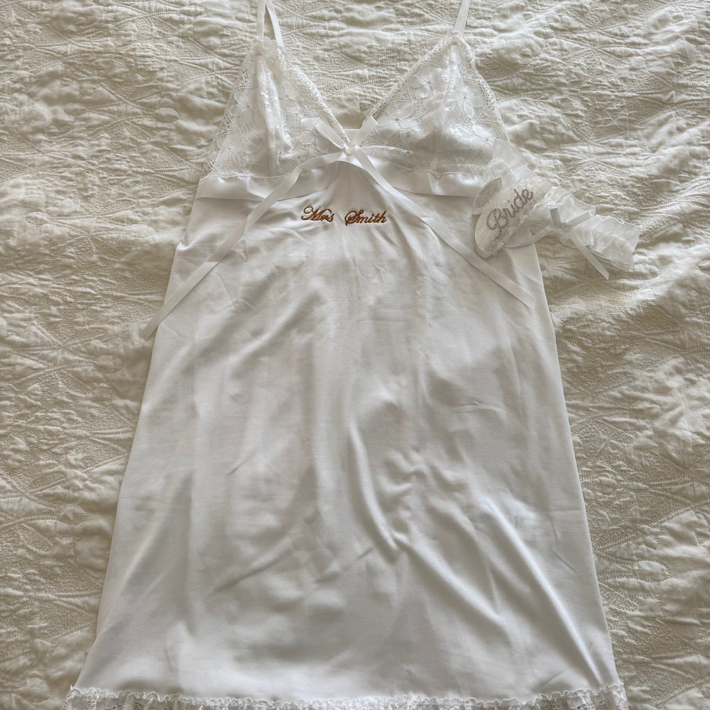 White lace nightgown on a wooden hanger against a textured beige background