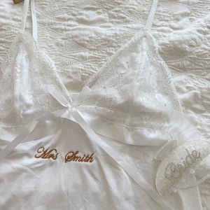 White lace garment with 'Mrs. Smith' embroidery on a textured surface