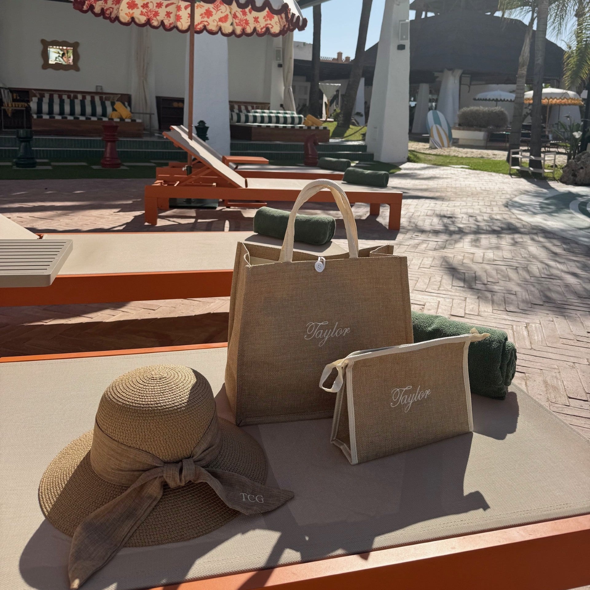Brown straw hat and bags on a table with a patio and palm trees in the background