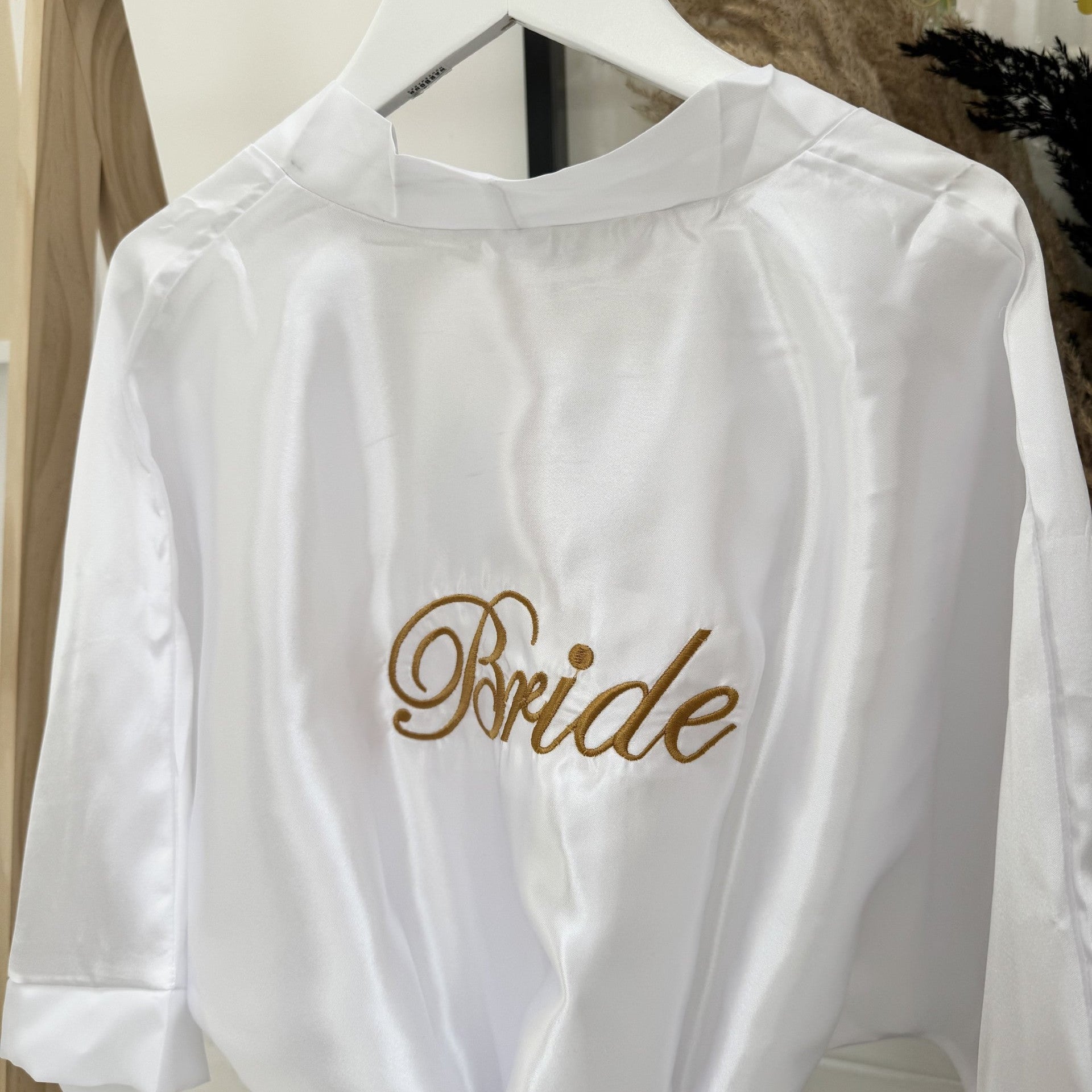 White satin robe with 'Bride' embroidery on a hanger.