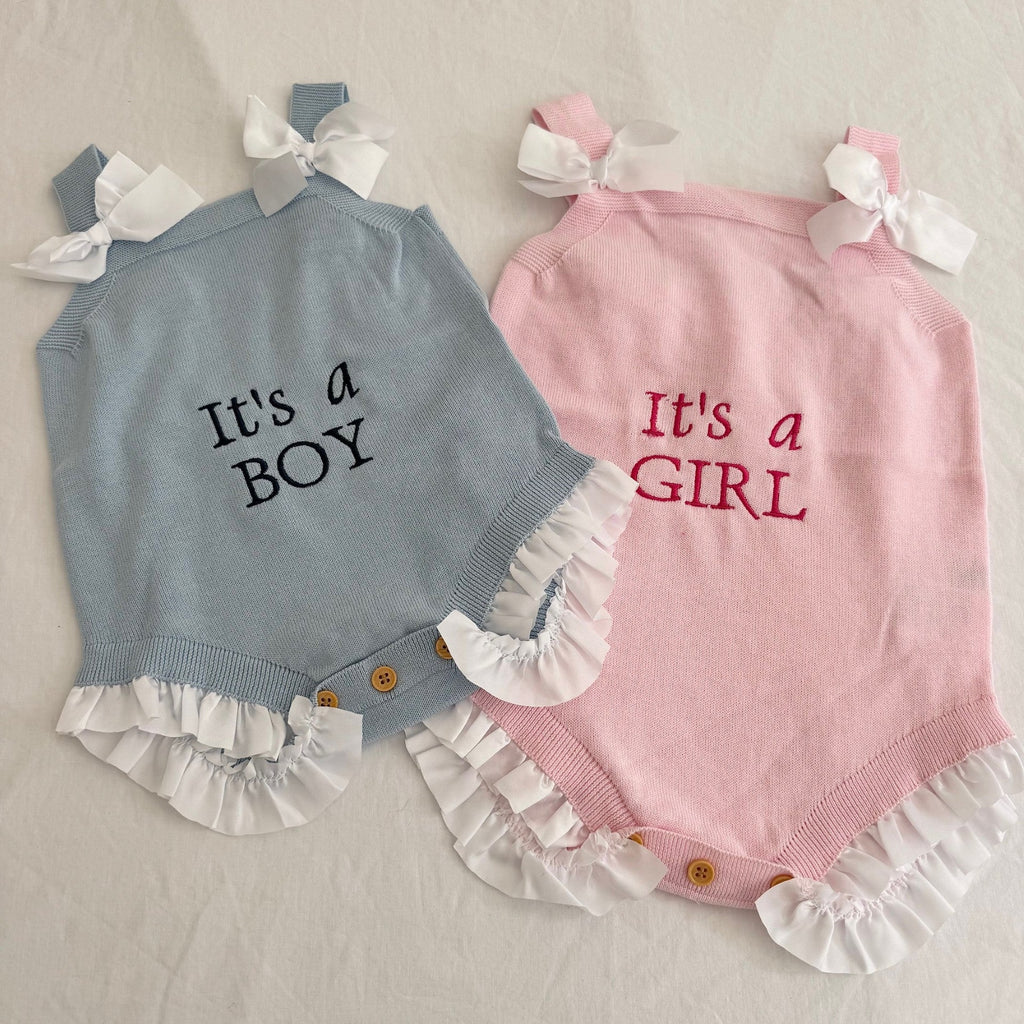 Two baby rompers, one blue with 'It's a Boy' text and one pink with 'It's a Girl' text, on a light background.