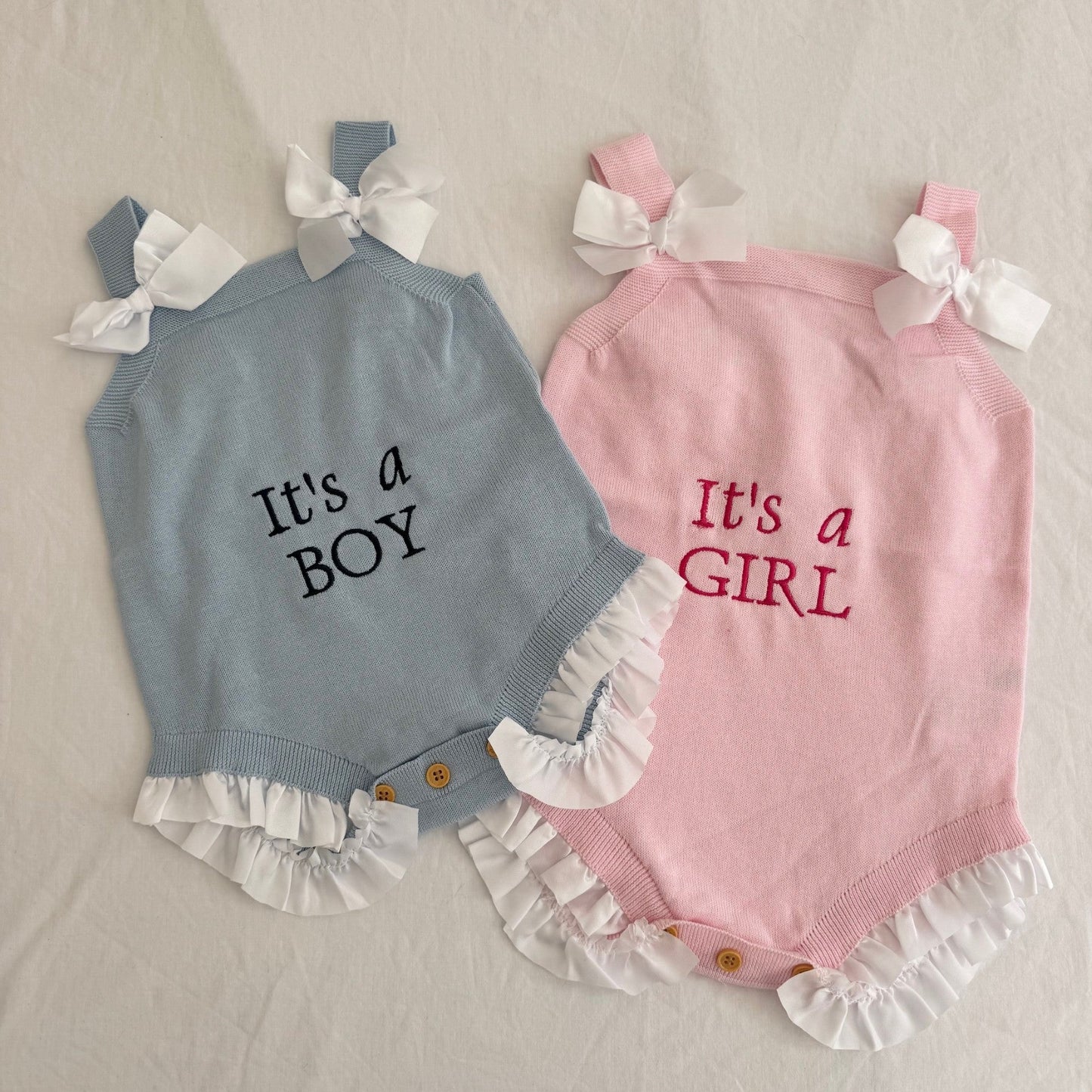 Two baby rompers, one blue and one pink, with 'It's a Boy' and 'It's a Girl' text respectively on a light background.