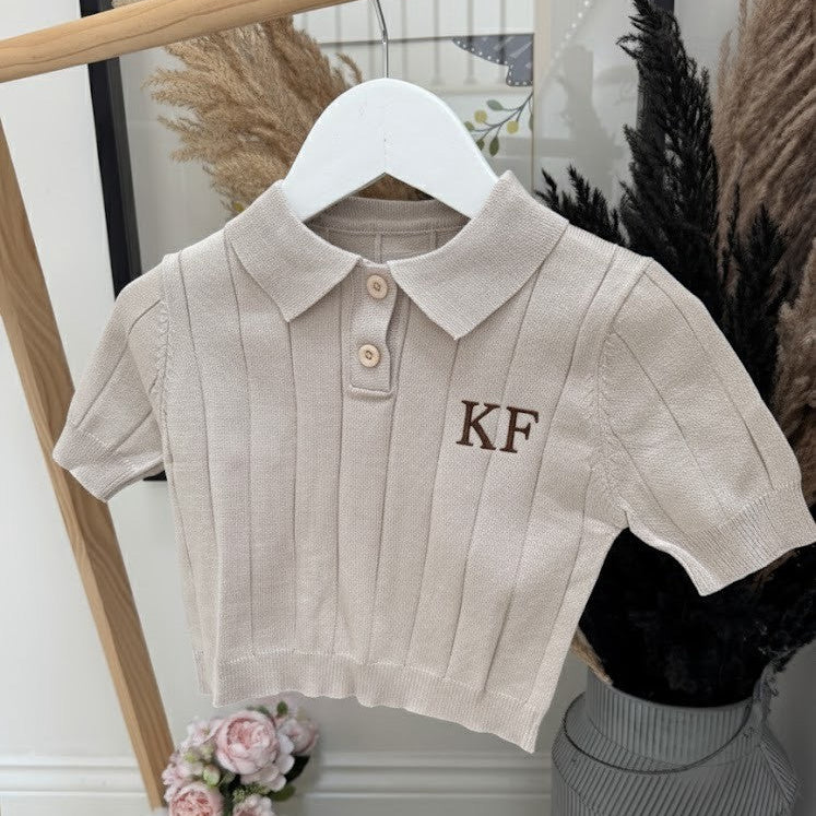 Beige ribbed polo shirt with 'KF' monogram on a hanger against a neutral background.