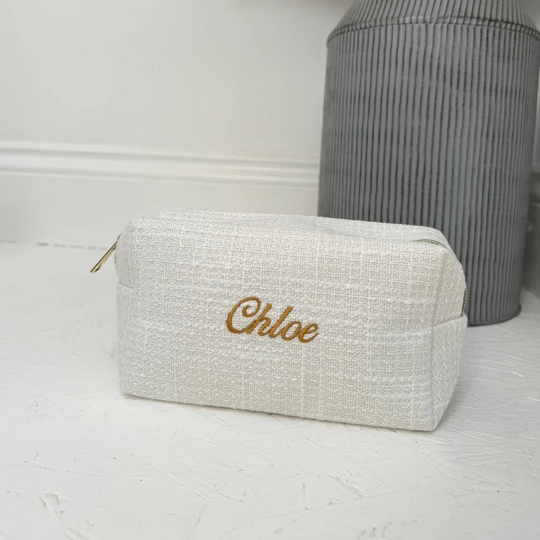 White textured pouch with 'Chloe' embroidery on a light wooden surface.
