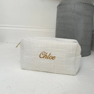 White textured pouch with 'Chloe' embroidery on a light wooden surface.