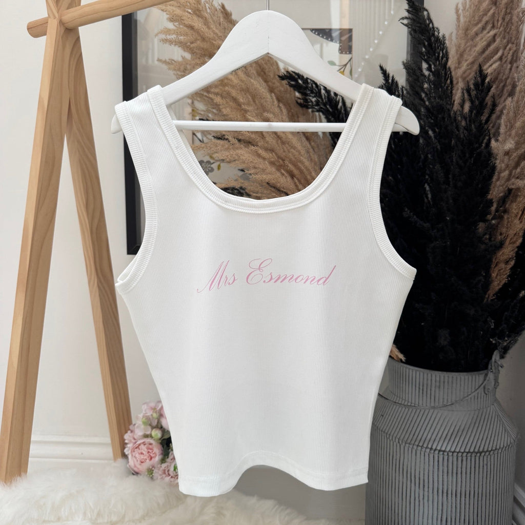 White tank top with 'Mrs. Esmond' text on a hanger against a neutral background