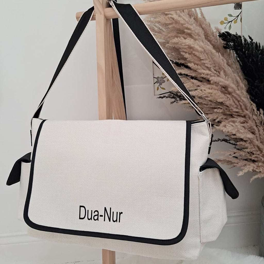 White bag with black accents and 'Dua-Nur' branding on a wooden stand.