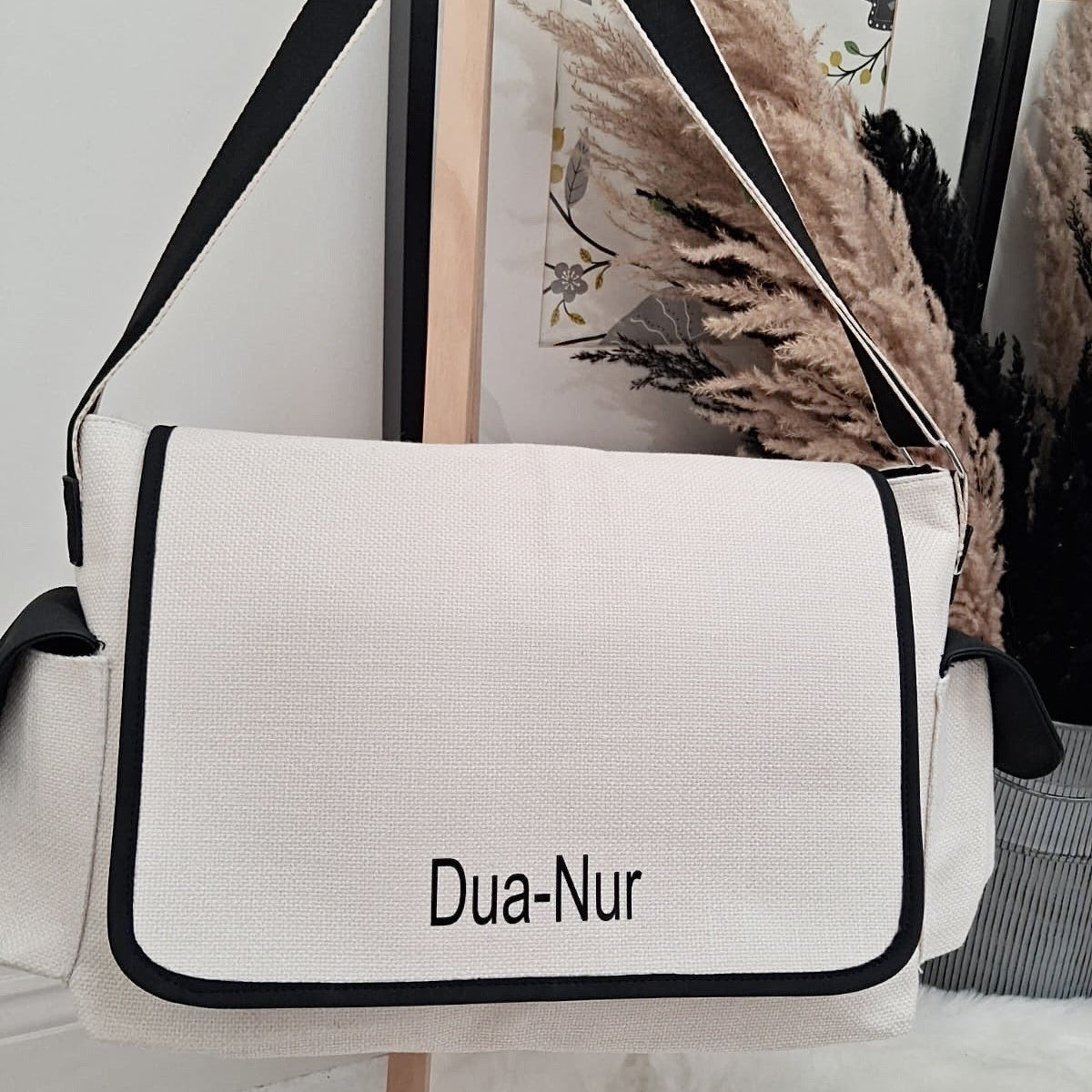 White bag with black accents and 'Dua-Nur' branding on a stand.