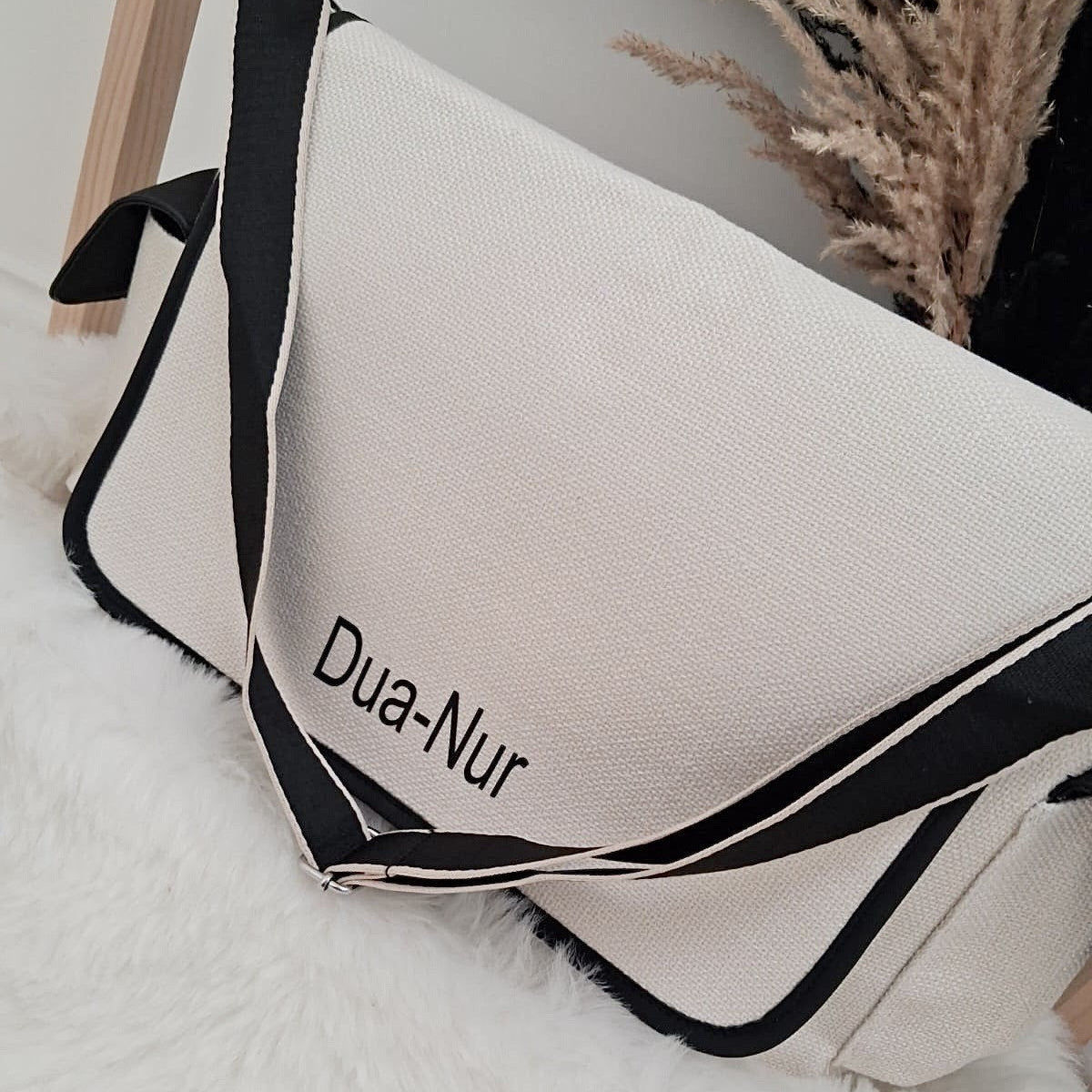 Baby carrier with 'Dua-Nur' branding on a soft surface