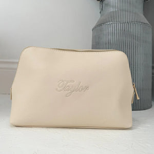 Beige pouch with 'Taylor' branding on a light gray background