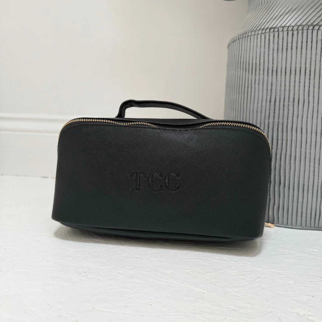 Black toiletry bag with 'TCC' branding on a light surface.