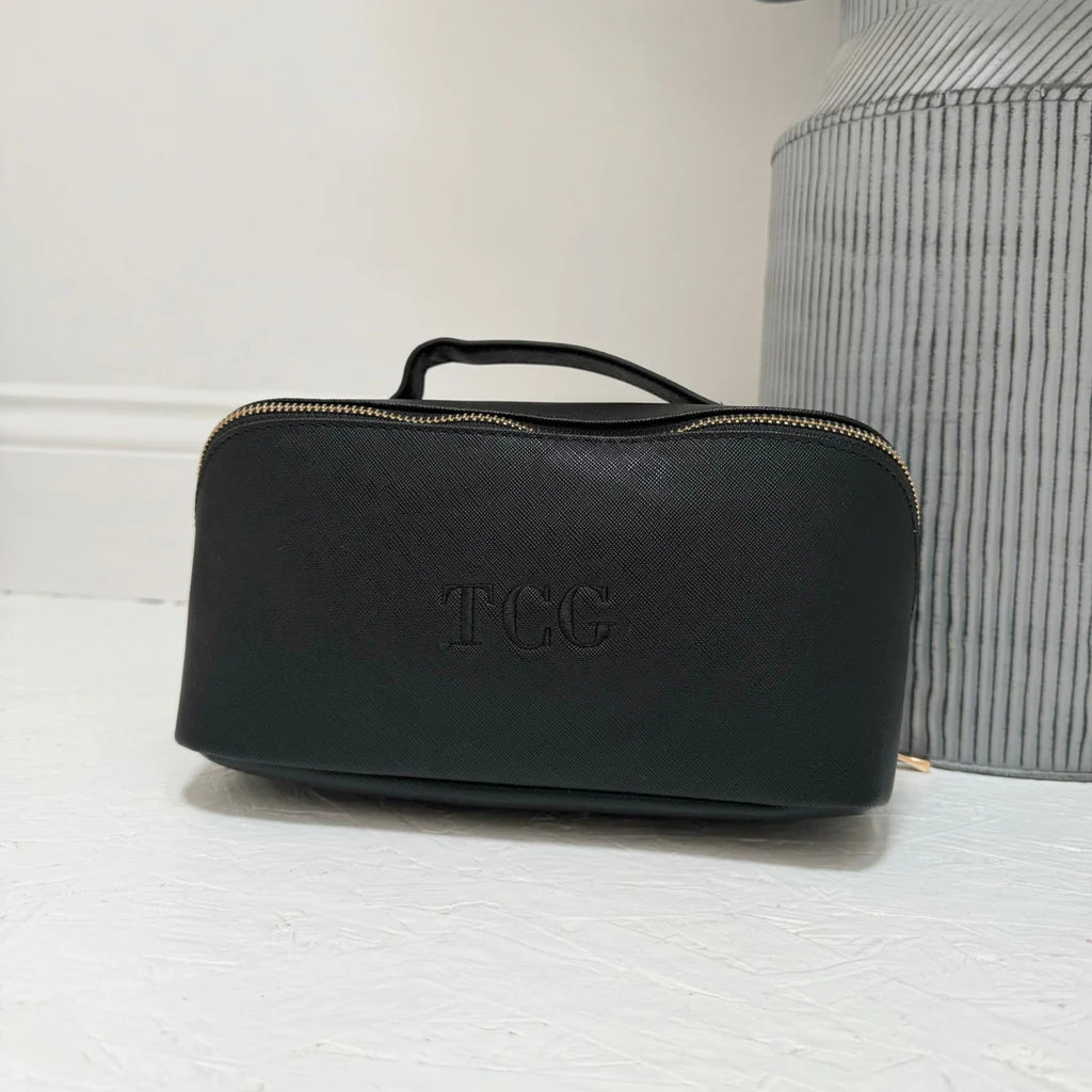 Black toiletry bag with 'TCC' branding on a light surface.
