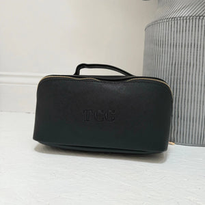 Black toiletry bag with 'TCC' branding on a light surface.