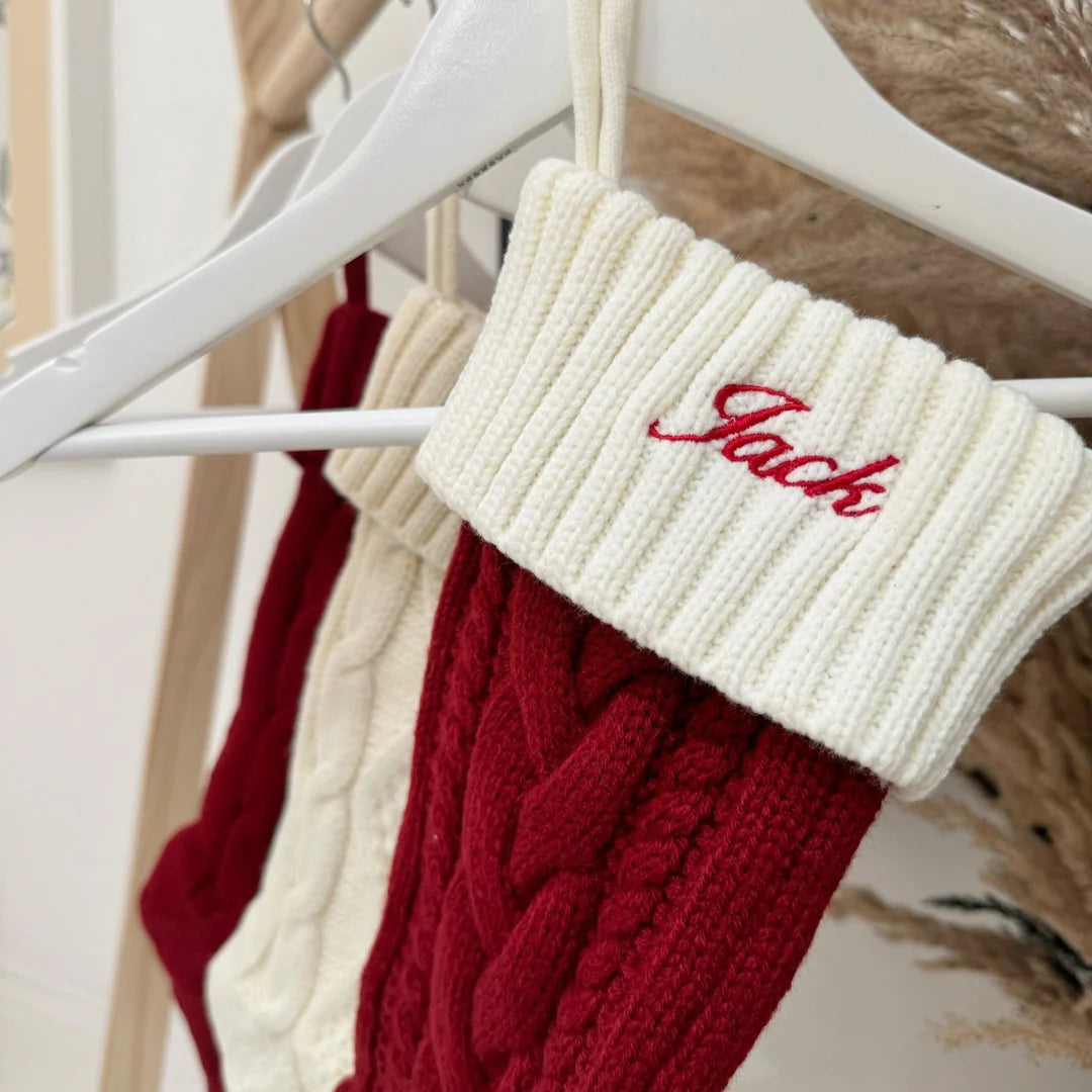 Red and cream knitted stockings with 'Jack' embroidered on a hanger.