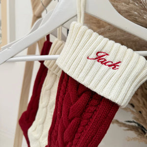 Red and cream knitted stockings with 'Jack' embroidered on a hanger.