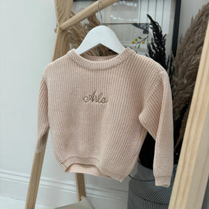 Beige sweater with 'Arlo' embroidery on a hanger against a neutral background