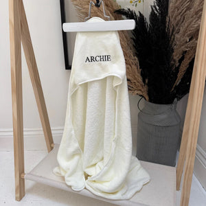 White towel with 'ARCHIE' branding on a wooden hanger against a neutral background