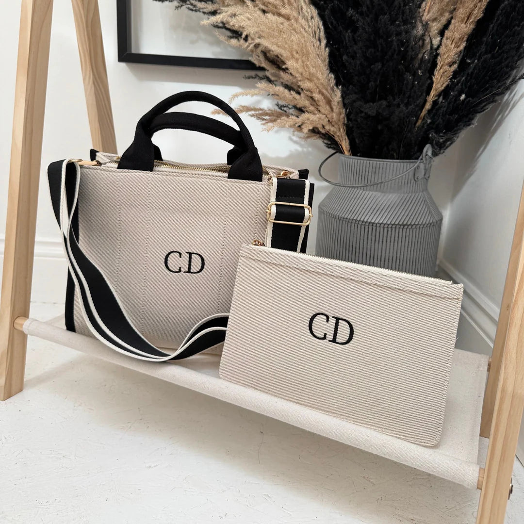 Handbag and pouch with 'CD' initials on a wooden shelf.