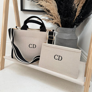 Handbag and pouch with 'CD' initials on a wooden shelf.