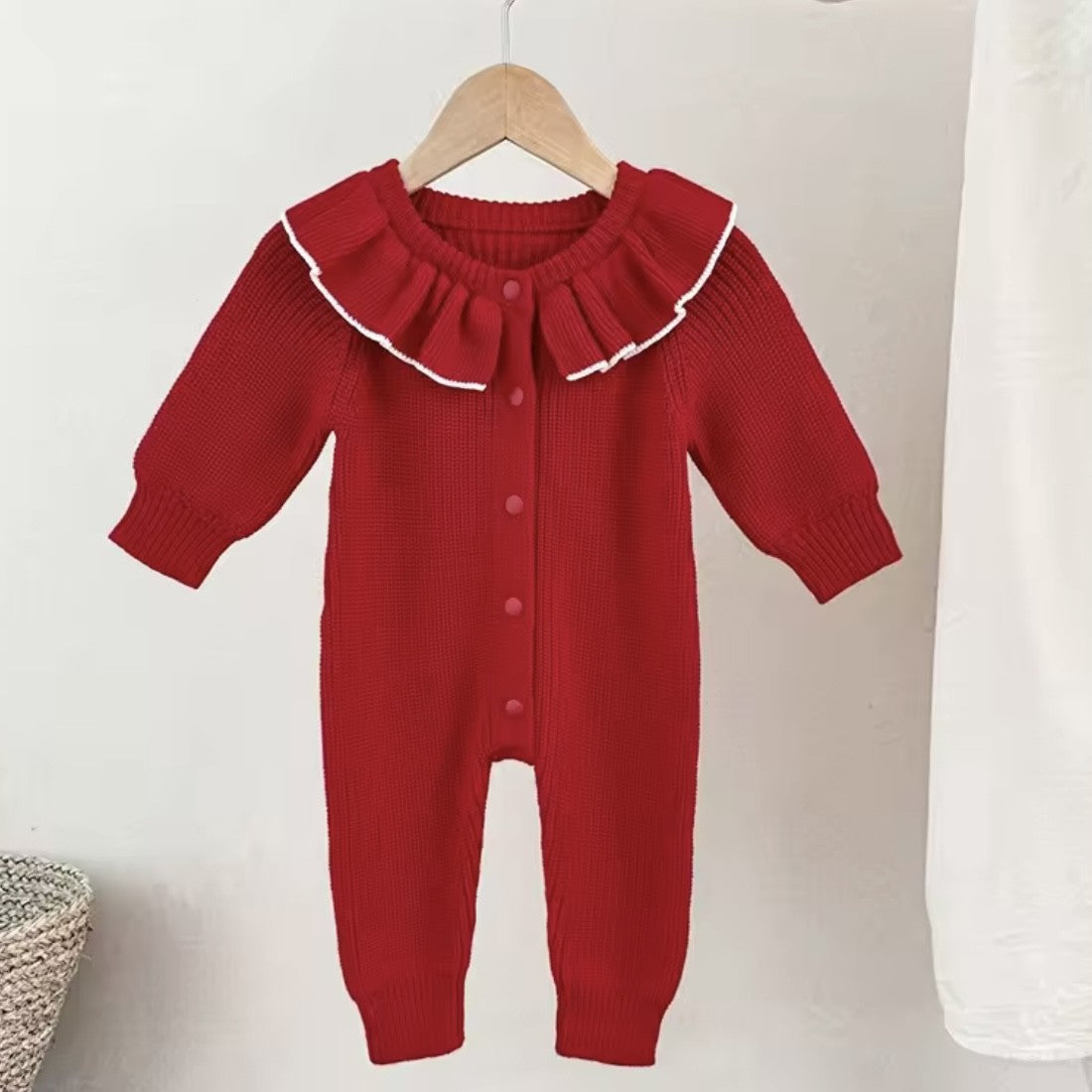 Red baby romper with ruffled collar on a wooden hanger against a white background