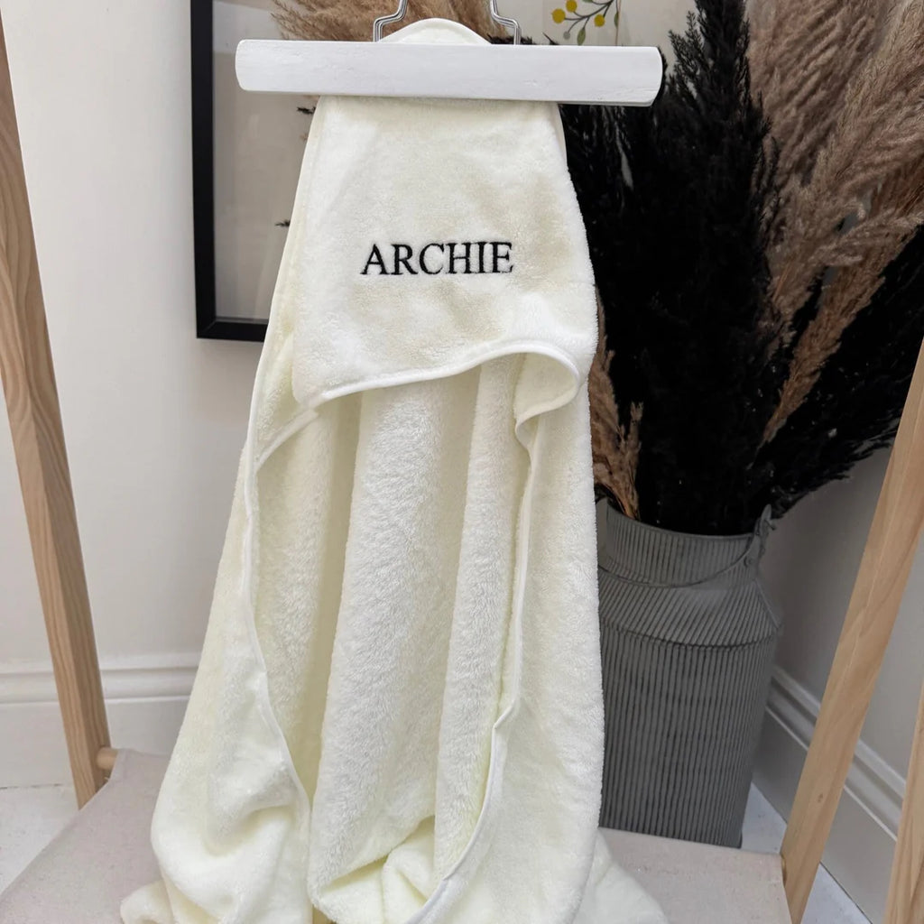 White towel with 'ARCHIE' embroidery on a hanger against a neutral background