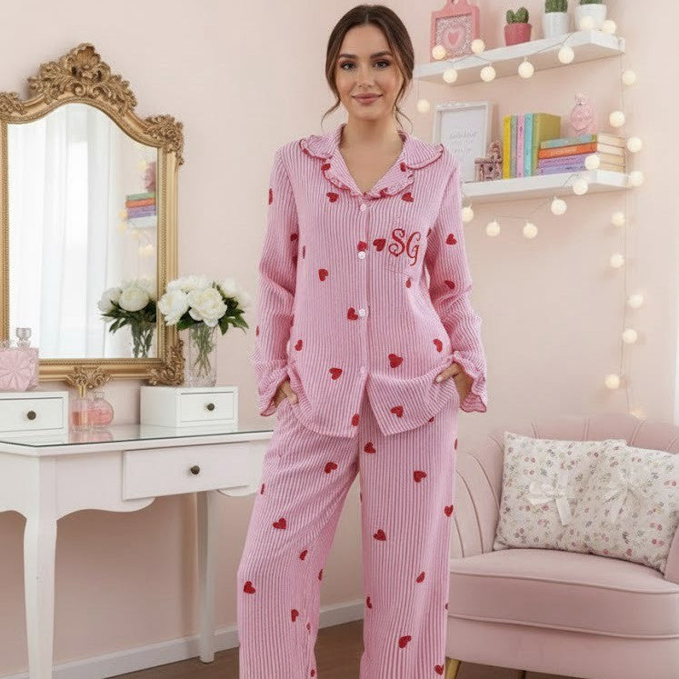 Woman wearing pink heart-patterned pajamas in a cozy room.