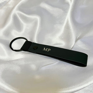 Black keychain with initials 'MP' on a white fabric background