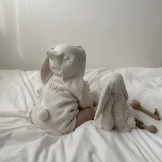 Baby Romper with 'Reign' embroidery on a white surface