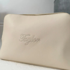Beige make up bag with 'Taylor' branding on a neutral background