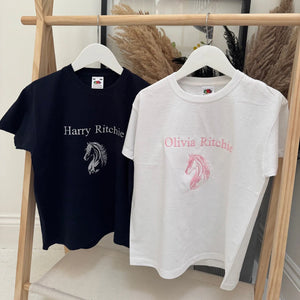 Two t-shirts with embroidered designs on hangers against a neutral background