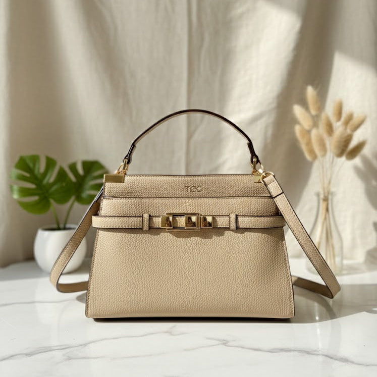 Beige handbag with gold accents on a light surface with a neutral background