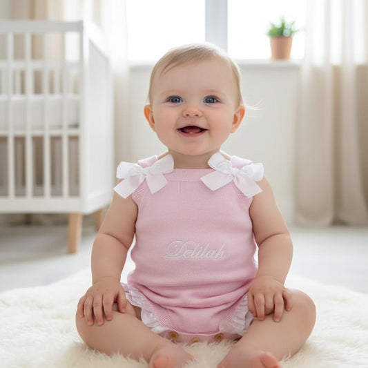 Baby wearing a pink outfit with white ruffles in a bright room