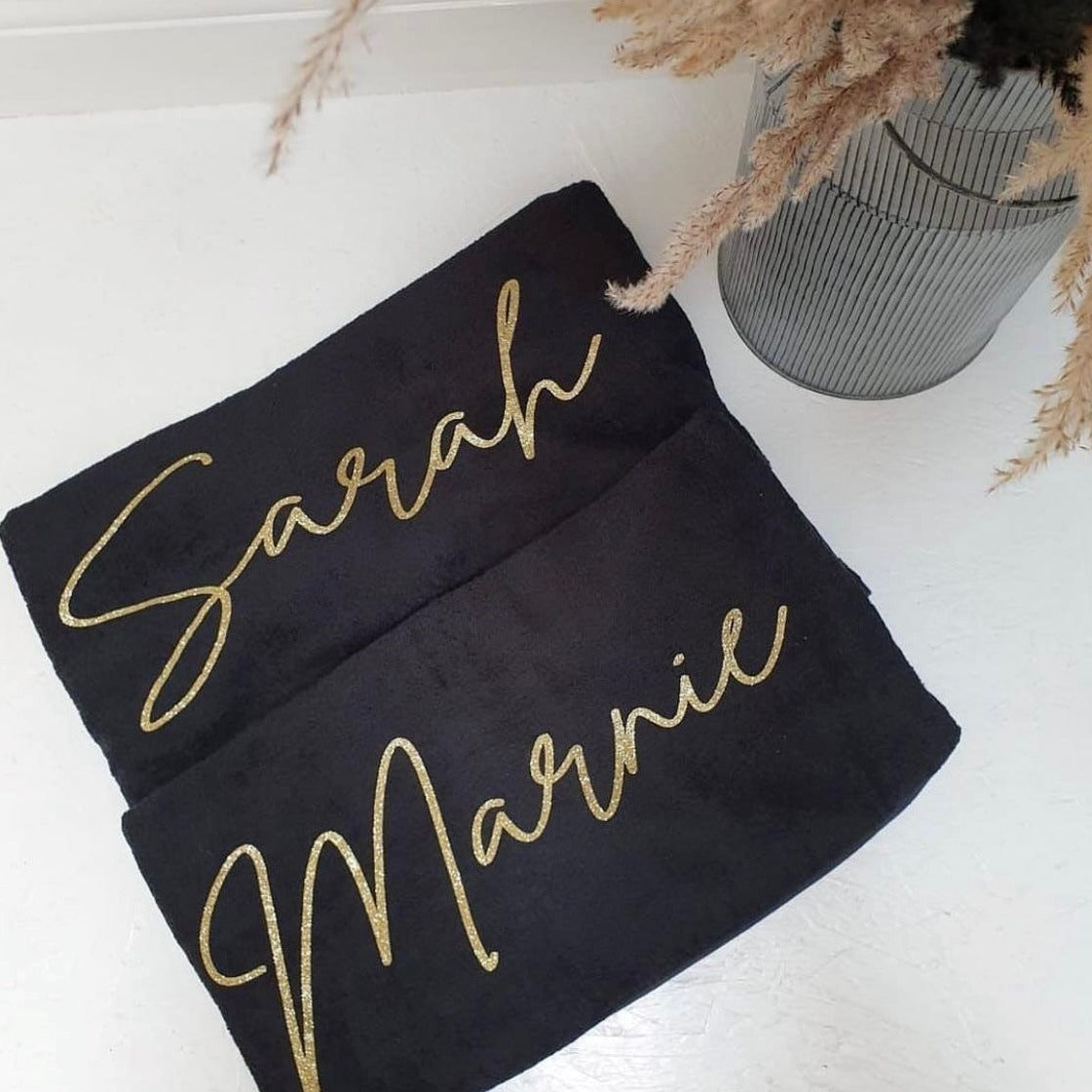 two personalised black towels on a white surface