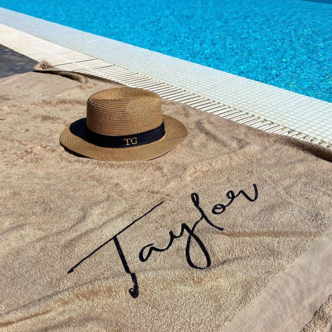 personalised towel by a pool with the name Taylor on it 